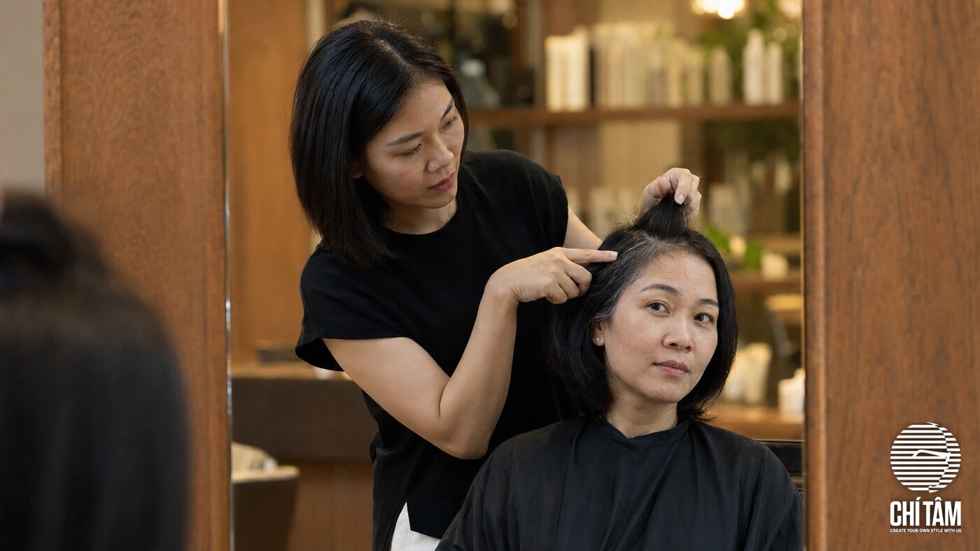 Stylist tư vấn màu nhuộm che tóc bạc cho khách tại salon
