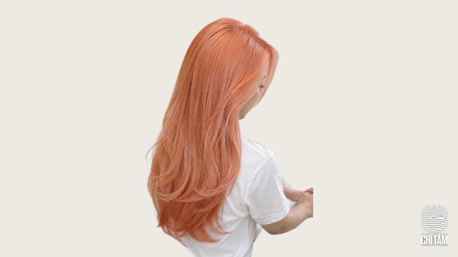 Tóc cam đào pastel chụp chéo sau, sắc cam pha hồng mềm trên tóc layer dài
